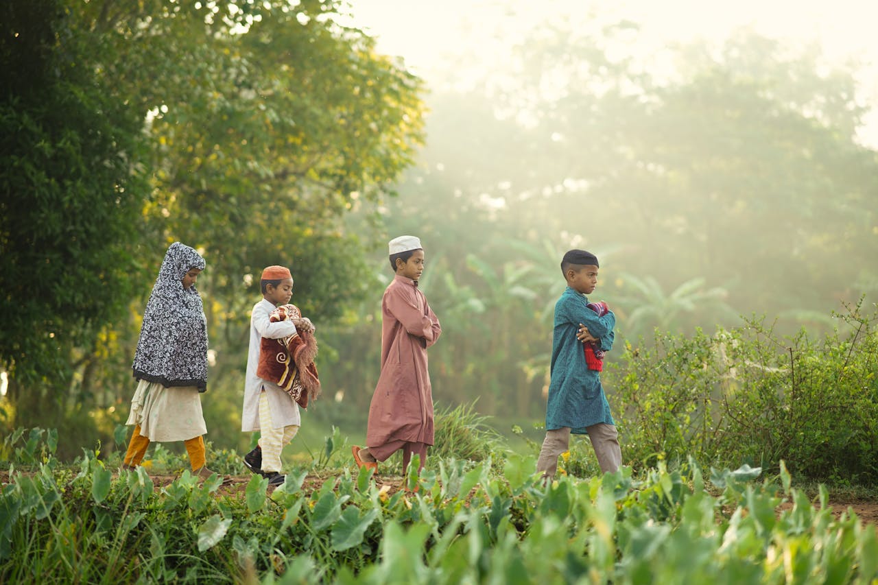 Children in traditional attire walking through lush greenery in Bangladesh, symbolizing cultural education.