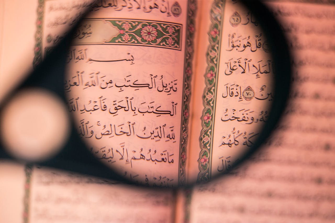 Close-up of Quranic pages through a magnifier, highlighting Arabic script.