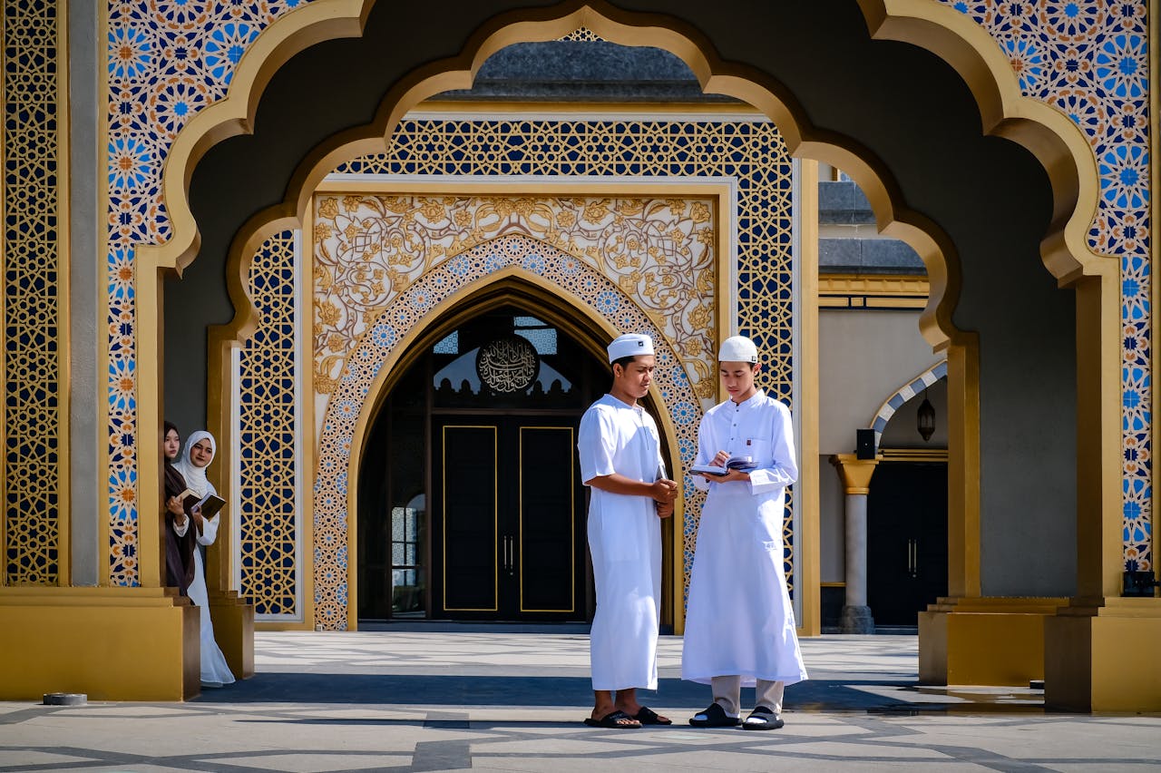 Group of young Muslims engaged in study at a mosque entrance.