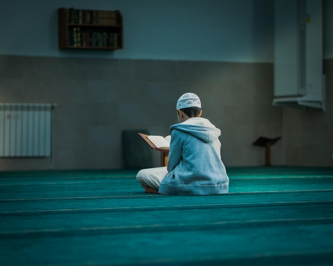 A boy in a mosque in Algeria reading religious texts, emphasizing peace and devotion.