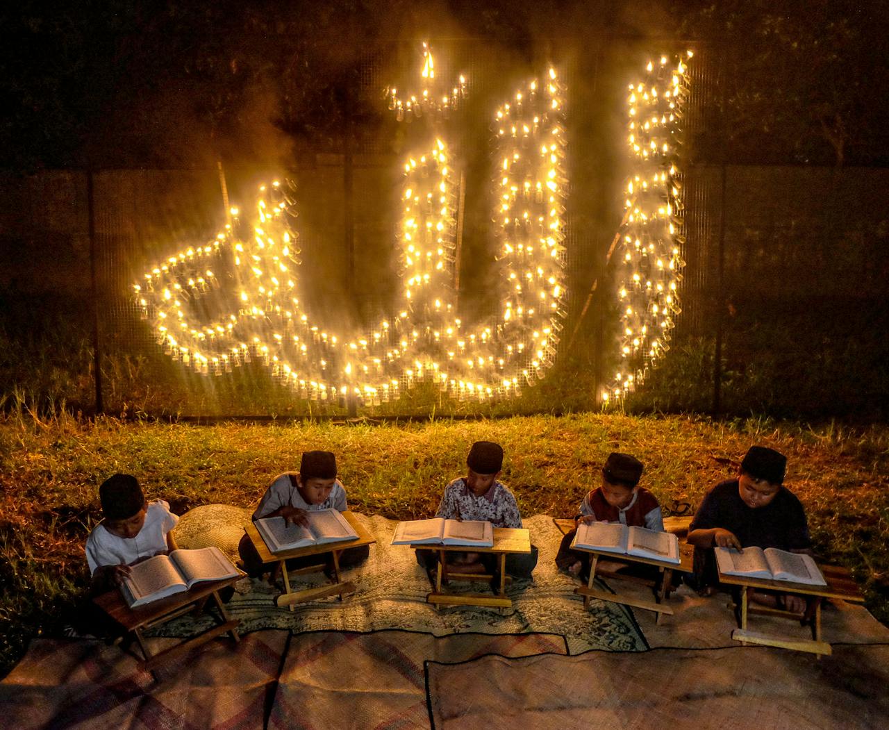 A group of children read the Quran under an illuminated Allah sign during Ramadan in Yogyakarta, Indonesia.